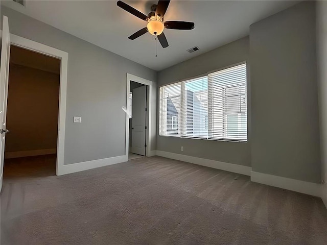 unfurnished bedroom featuring a walk in closet, ceiling fan, a closet, and carpet floors