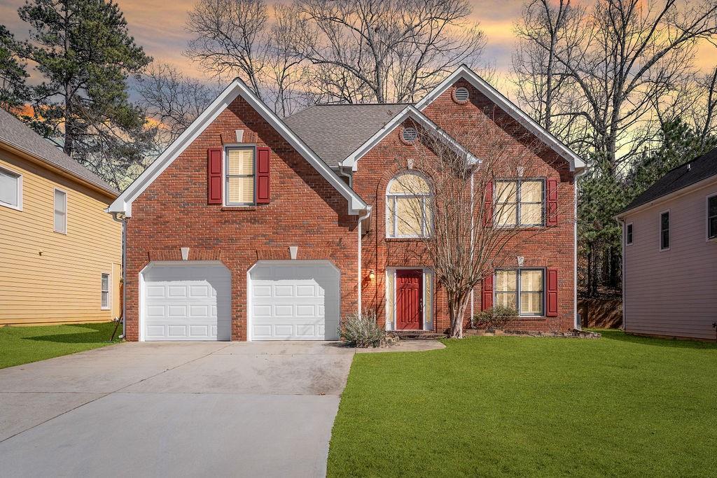 view of front of home featuring a garage, a yard, concrete driveway, and brick siding