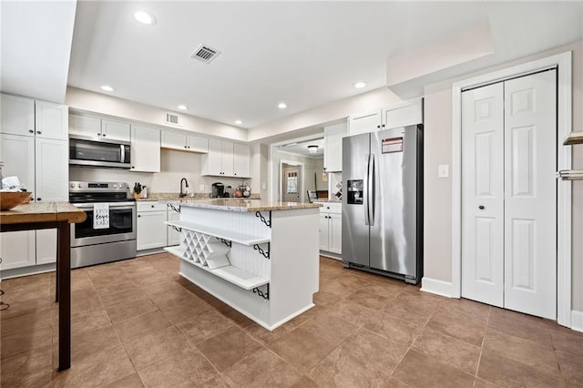 kitchen featuring light stone countertops, white cabinetry, and appliances with stainless steel finishes