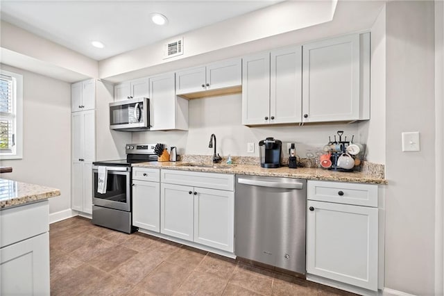 kitchen with sink, white cabinets, light stone counters, and appliances with stainless steel finishes