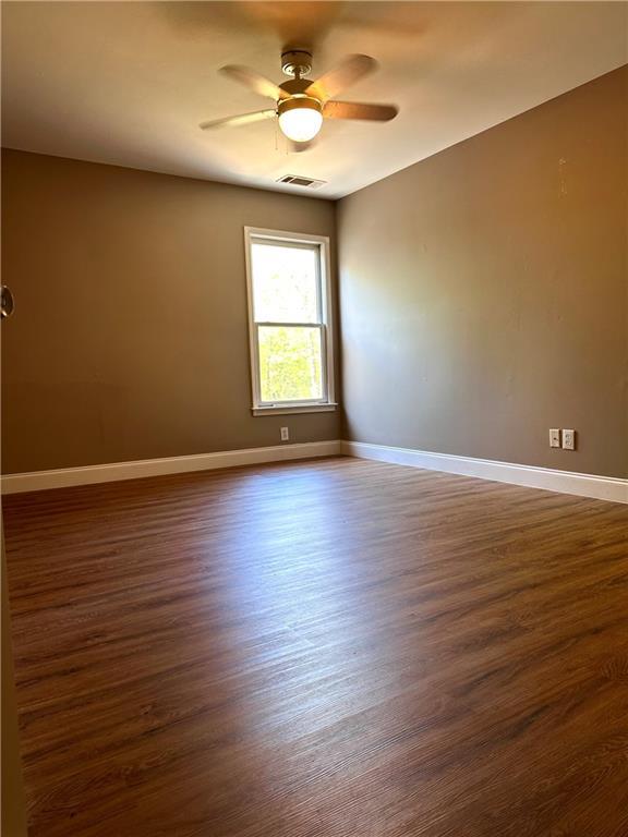 225 Austin Oaks Dr SE, Ellenwood, GA 30294 - spare room featuring visible vents, baseboards, a ceiling fan, and dark wood-style floors