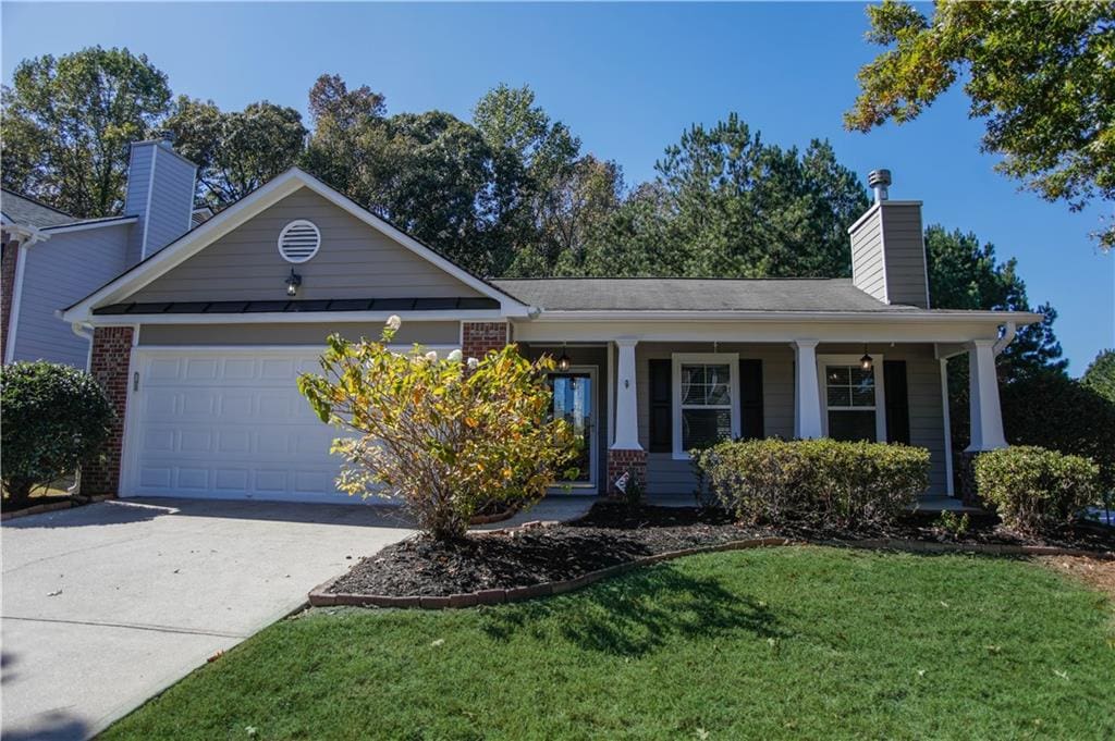 view of front of house with a front yard, covered porch, and a garage