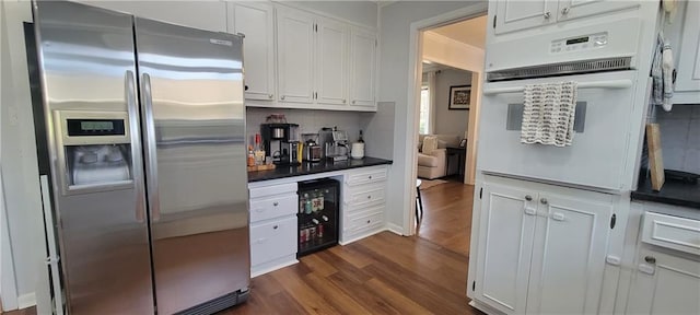 kitchen featuring dark wood-type flooring, wine cooler, stainless steel refrigerator with ice dispenser, white cabinetry, and white oven