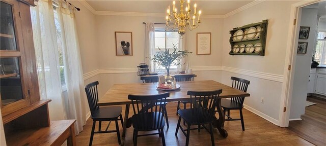 dining room featuring a chandelier, crown molding, baseboards, and wood finished floors