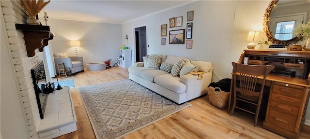 living area with crown molding, a brick fireplace, and wood finished floors