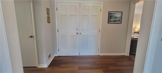 corridor with dark wood-style floors, visible vents, and baseboards