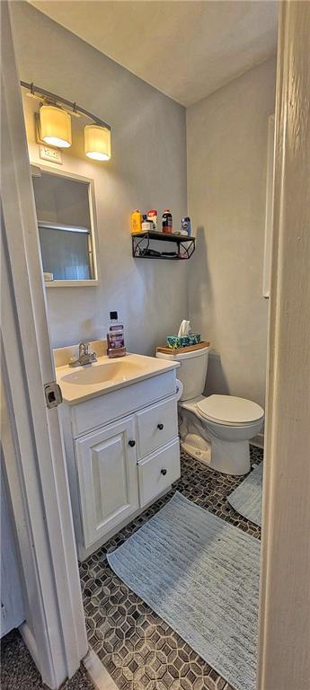 bathroom featuring tile patterned flooring, toilet, and vanity