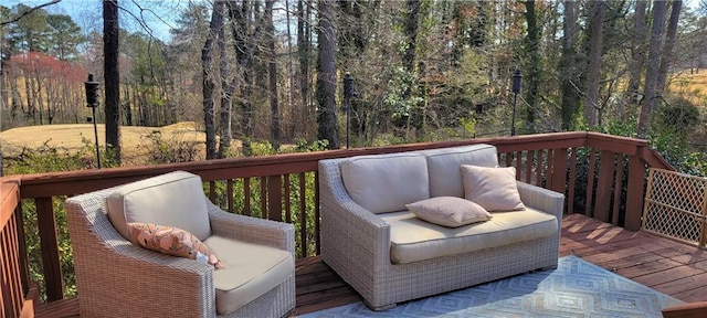 wooden terrace featuring an outdoor living space and a view of trees