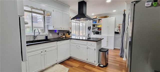 kitchen with a sink, stainless steel appliances, a healthy amount of sunlight, and island range hood