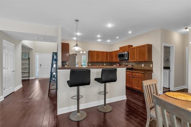812 Roget Way, Lawrenceville, GA 30045 - kitchen with appliances with stainless steel finishes, brown cabinetry, a kitchen breakfast bar, dark wood-style floors, and recessed lighting