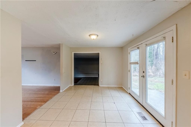 unfurnished room featuring light tile patterned floors, a textured ceiling, and french doors