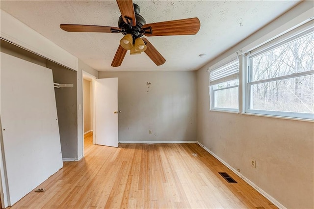 unfurnished bedroom with ceiling fan, a closet, light hardwood / wood-style flooring, and a textured ceiling