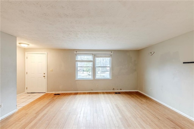 unfurnished room featuring light hardwood / wood-style flooring and a textured ceiling