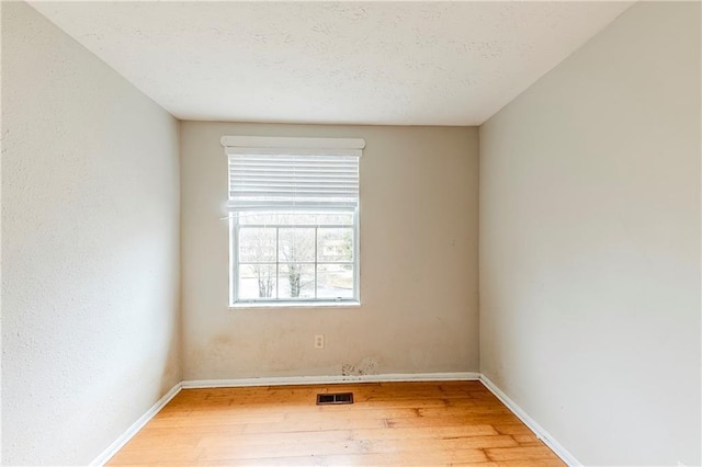 empty room with hardwood / wood-style flooring and a textured ceiling