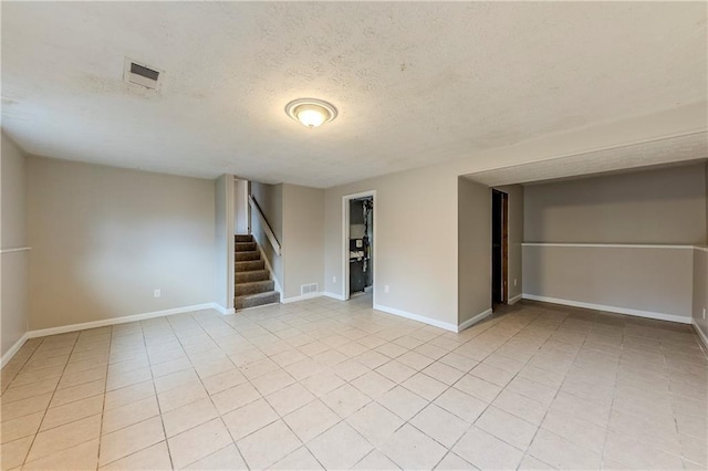 spare room with a textured ceiling and light tile patterned flooring