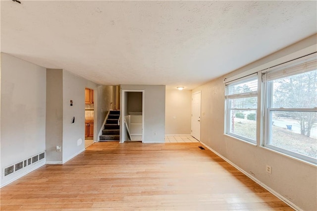 empty room featuring a textured ceiling and light hardwood / wood-style flooring