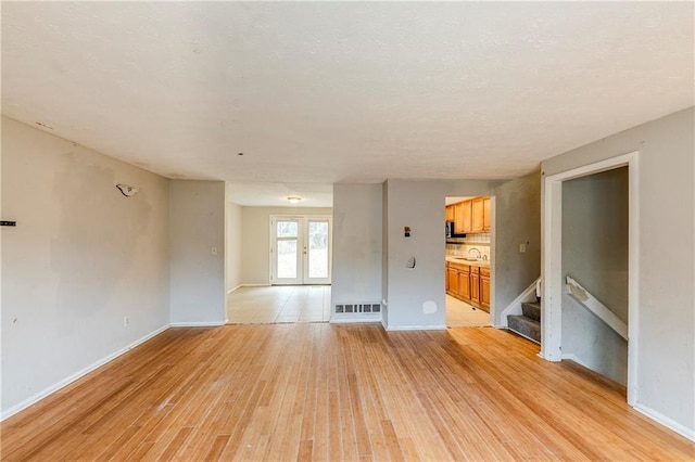 unfurnished living room with sink and light hardwood / wood-style floors