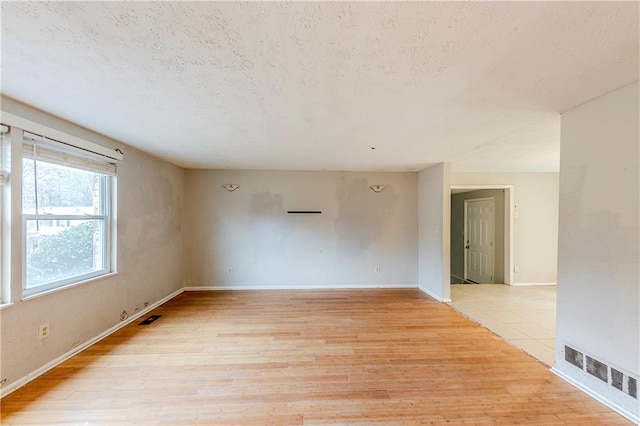 unfurnished room featuring light hardwood / wood-style floors and a textured ceiling