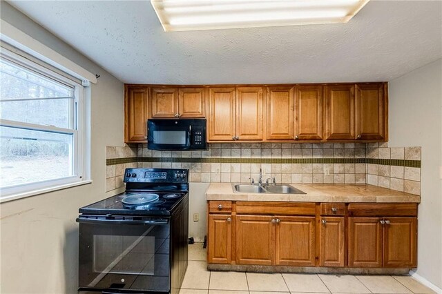 kitchen featuring backsplash, black appliances, sink, and light tile patterned flooring