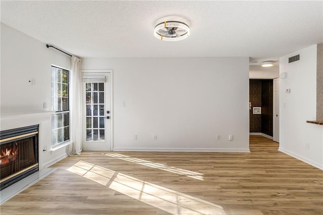 unfurnished living room with light hardwood / wood-style floors and a textured ceiling