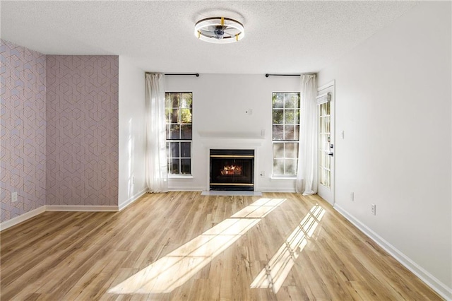 unfurnished living room featuring a textured ceiling and light hardwood / wood-style floors