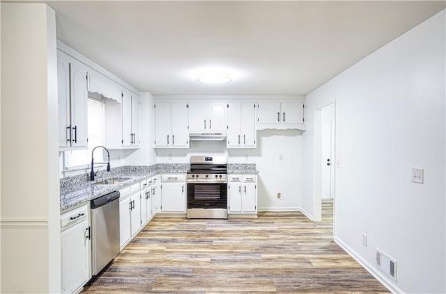 kitchen featuring stainless steel appliances, sink, white cabinetry, light stone counters, and light hardwood / wood-style flooring