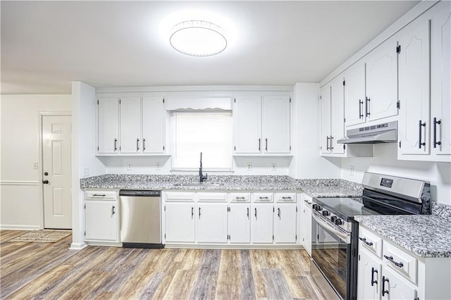 kitchen with hardwood / wood-style floors, appliances with stainless steel finishes, light stone countertops, white cabinets, and sink