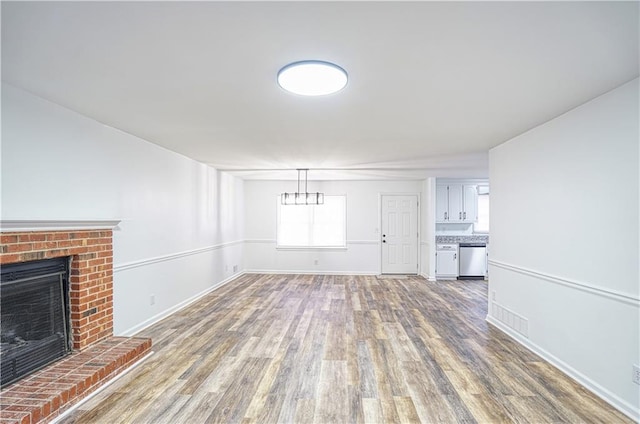 unfurnished living room with wood-type flooring and a brick fireplace