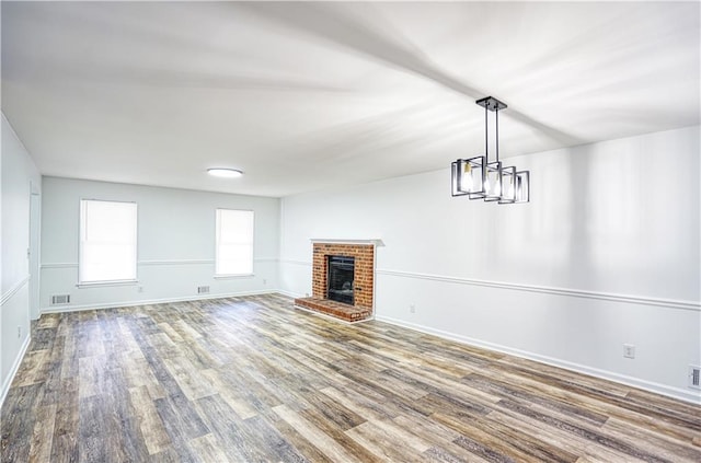 unfurnished living room with a fireplace, hardwood / wood-style floors, and a notable chandelier