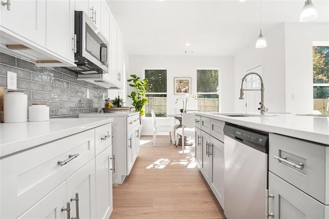 kitchen featuring sink, white cabinetry, stainless steel appliances, decorative backsplash, and decorative light fixtures