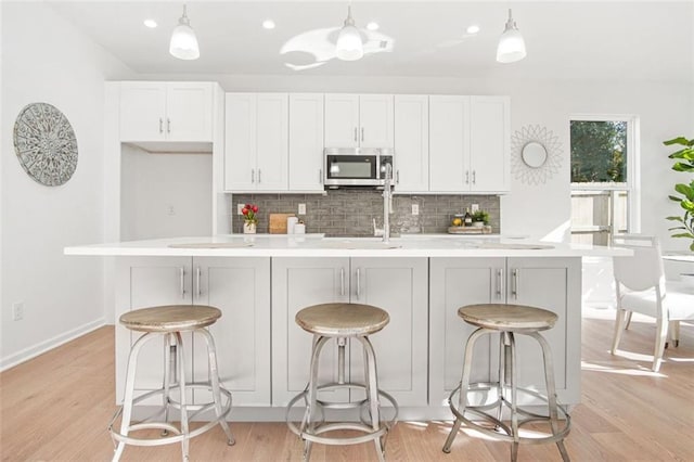 kitchen featuring an island with sink, a kitchen bar, and decorative light fixtures