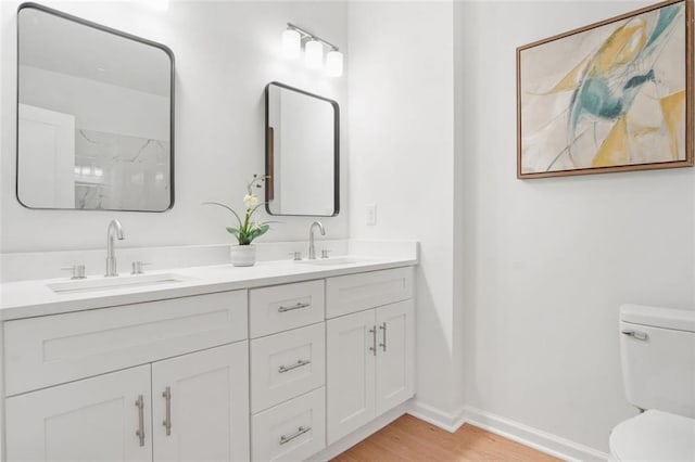 bathroom featuring hardwood / wood-style flooring, vanity, walk in shower, and toilet