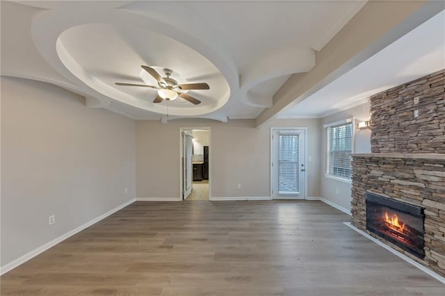 unfurnished living room featuring a stone fireplace, wood-type flooring, and ceiling fan