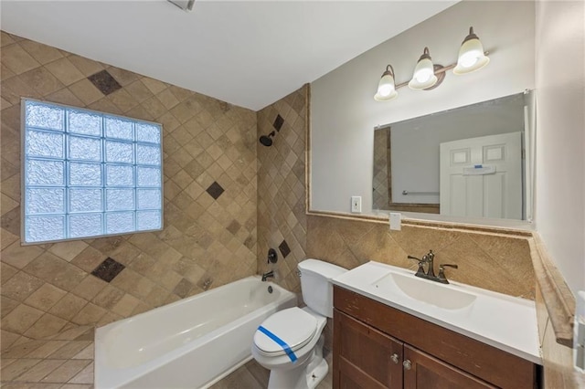 full bathroom with tile walls, vanity, toilet, and tiled shower / bath