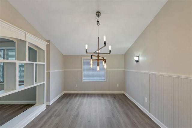 unfurnished dining area with hardwood / wood-style flooring, lofted ceiling, and an inviting chandelier