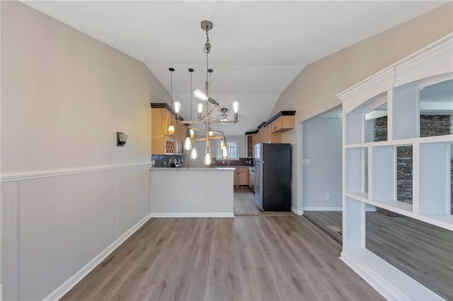 kitchen with stainless steel refrigerator, a barn door, light brown cabinetry, and pendant lighting