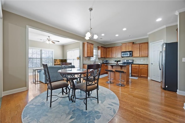 dining area with baseboards, crown molding, and light wood-style floors