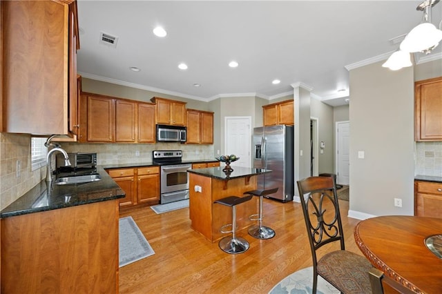 kitchen featuring light wood-type flooring, appliances with stainless steel finishes, a breakfast bar, and a sink