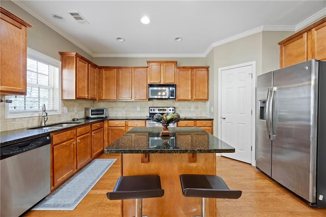 kitchen featuring a sink, visible vents, appliances with stainless steel finishes, light wood-type flooring, and a center island