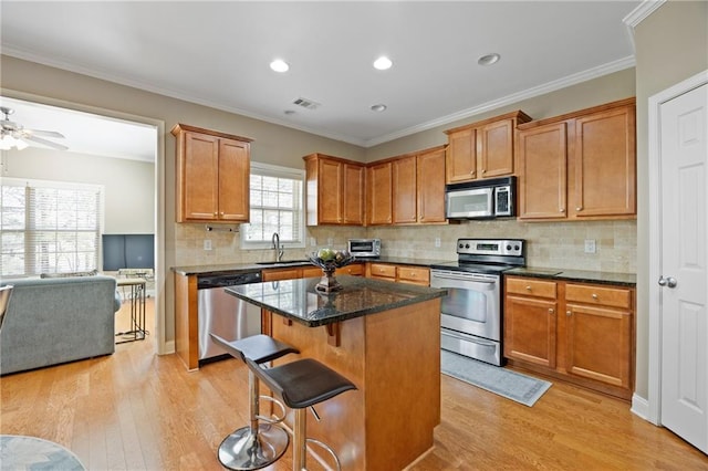 kitchen featuring appliances with stainless steel finishes, light wood-type flooring, visible vents, and a kitchen island