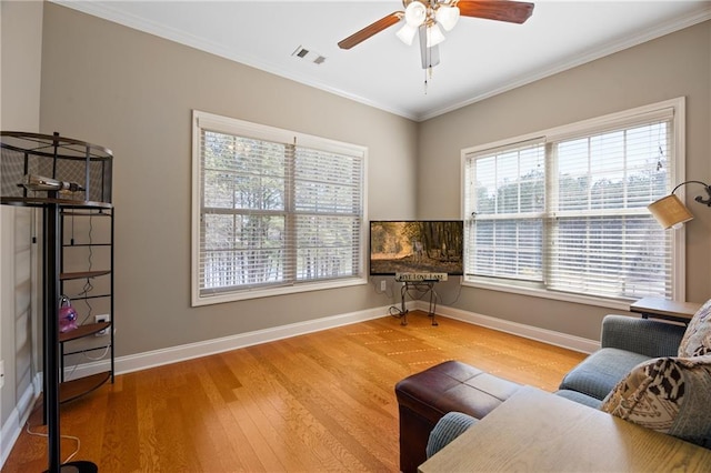 sitting room featuring baseboards, visible vents, wood finished floors, and ornamental molding