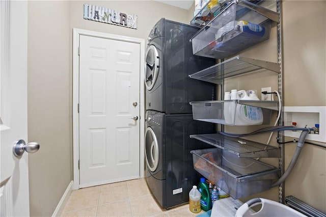 washroom with stacked washer and dryer, tile patterned flooring, laundry area, and baseboards