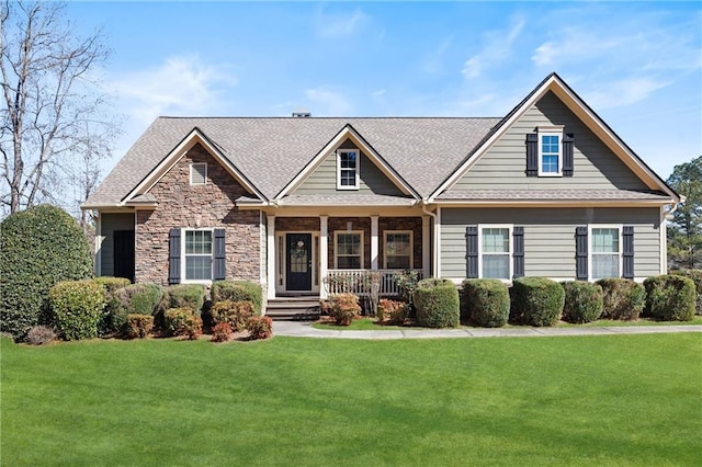 craftsman-style house with a porch, stone siding, a shingled roof, and a front lawn