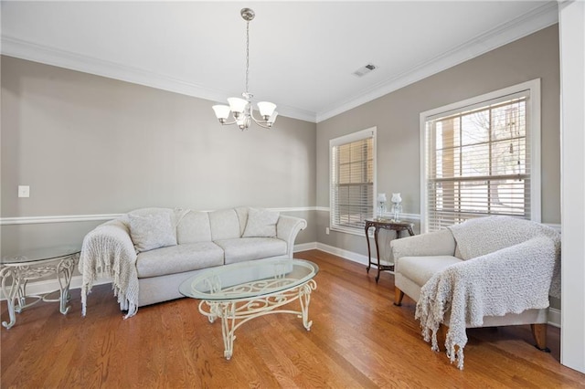 living room with visible vents, baseboards, wood finished floors, an inviting chandelier, and crown molding