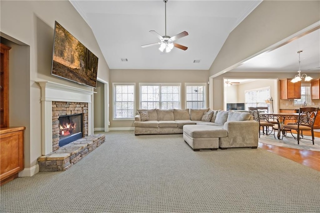 carpeted living room with a wealth of natural light, visible vents, a fireplace, and ceiling fan with notable chandelier