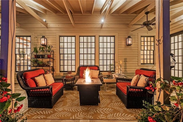 interior space with beamed ceiling, wooden walls, and ceiling fan