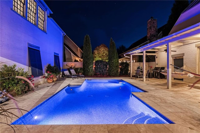 pool at twilight featuring ceiling fan, area for grilling, and a patio area