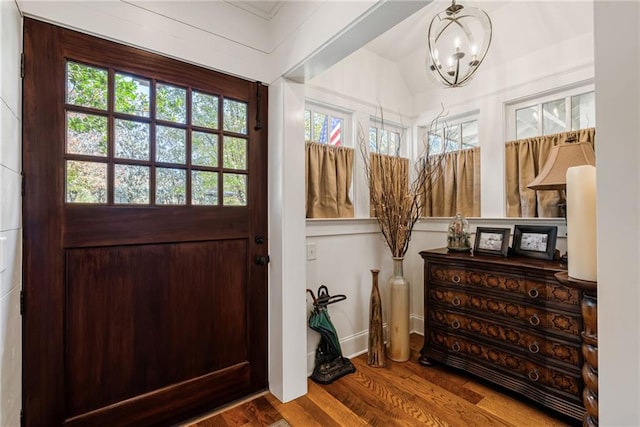 foyer entrance with lofted ceiling, wood-type flooring, and a chandelier