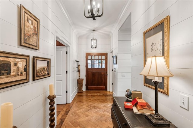 entryway featuring ornamental molding, a chandelier, and light parquet floors