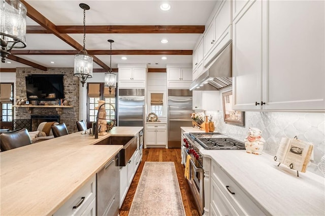 kitchen featuring high end appliances, pendant lighting, sink, and white cabinets